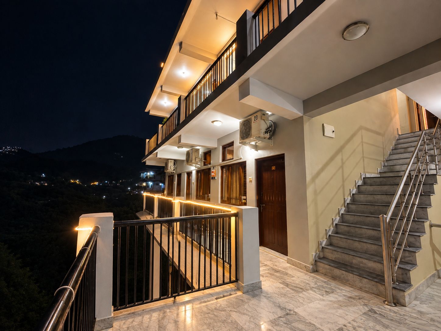 A multi-story hotel with a staircase, balconies, and a view of the surrounding landscape.