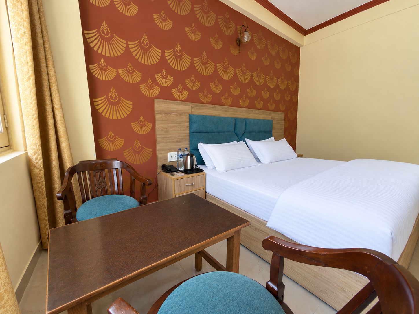 A hotel room with a bed, a wooden nightstand, a table, and two chairs.