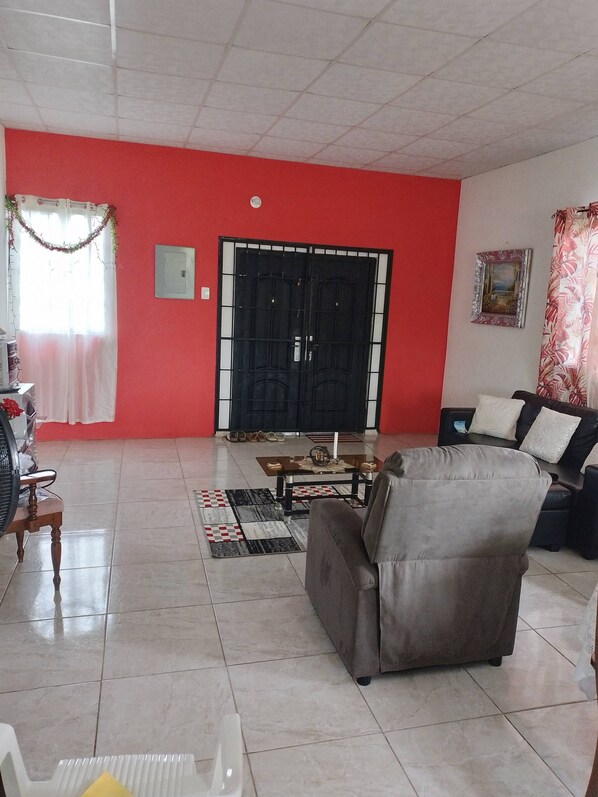 Una sala de estar con una pared roja, un portón negro, un sofá, una mesa de centro y una alfombra estampada.