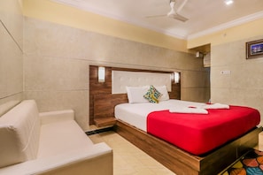Une chambre d’hôtel équipée d’un lit, d’une chaise, d’un ventilateur de plafond et d’un climatiseur fixé au mur.