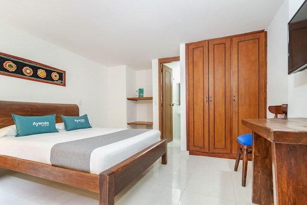Une chambre d’hôtel avec un lit en bois, un bureau, une chaise et une armoire.