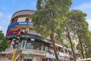 Un edificio de varios pisos con diversas tiendas en la planta baja, incluyendo una farmacia y una clínica de cuidado visual.