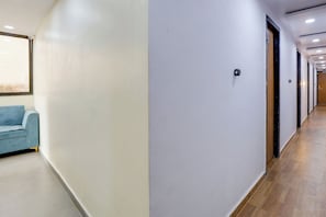 Un pasillo con un sofá azul, una pared texturizada y una puerta con cámara de seguridad.