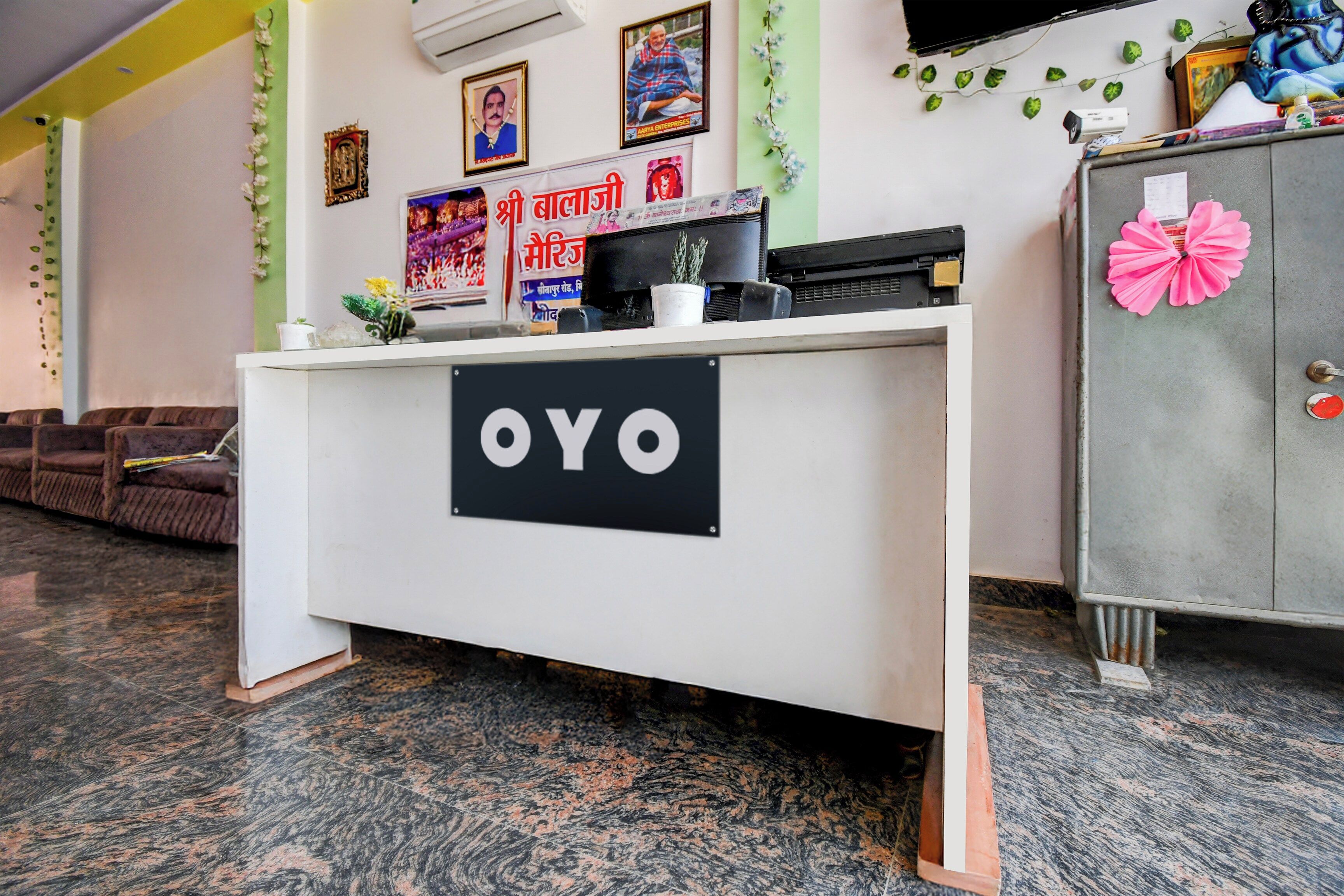 A reception desk with a sign that reads 'OYO' in a hotel lobby with a sofa and a cabinet.