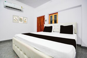 Een hotelkamer met een bed, een raam en een airconditioning.