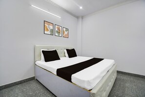Een hotelkamer met een bed, een hoofdeinde, een wandlamp en drie ingelijste foto's.