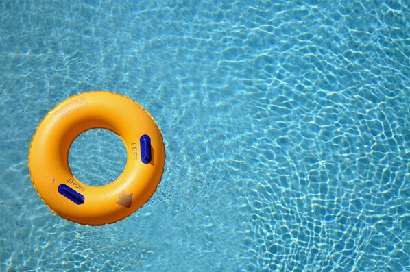 Un anneau gonflable jaune flottant sur une eau d’un bleu limpide.