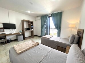 Ett hotellrum med en säng, ett skrivbord, en tv, en garderob och ett fönster med gardiner.