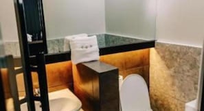 Pieni kylpyhuone, jossa on wc, pesuallas ja peili.