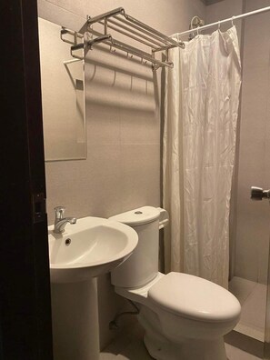 Kylpyhuone, jossa on wc, pesuallas ja suihkuverho.