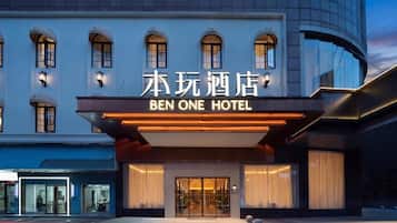 A hotel entrance with a modern facade, illuminated signage, and a glass door entrance.