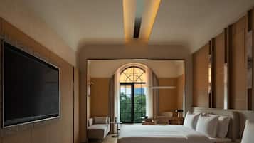 A hotel room with a large bed, a TV, and a view of the outdoors through a window.