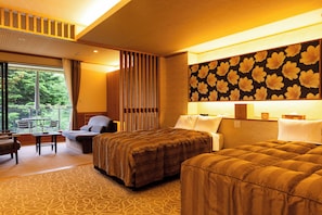 Een hotelkamer met een bed, een bank, een eettafel en uitzicht op de omgeving.