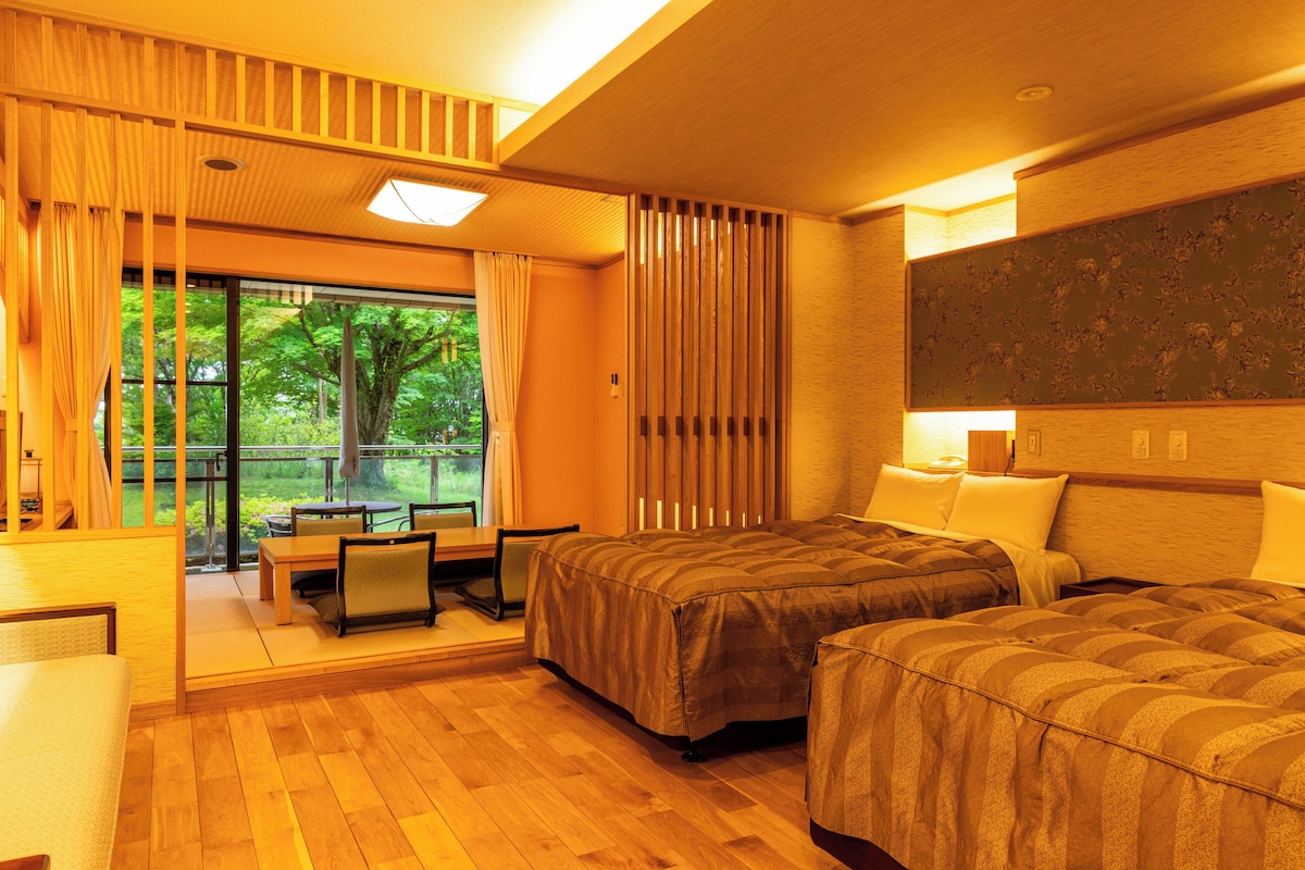 Een hotelkamer met balkon, bed, bureau en stoel.