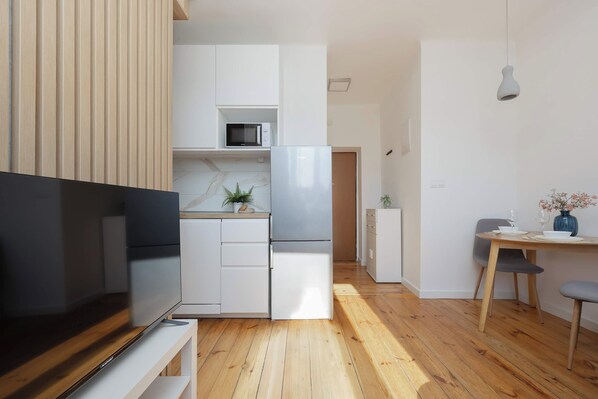 A modern kitchen with a built-in microwave, refrigerator, and wooden cabinets. - Warsaw | Staszica 4 | Bright Studio | Mezzanine (Warszawa)