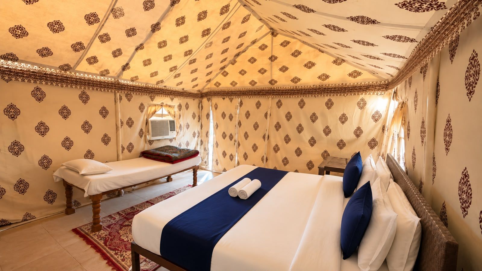 Una habitación con cama, un banco y un papel tapiz decorado.