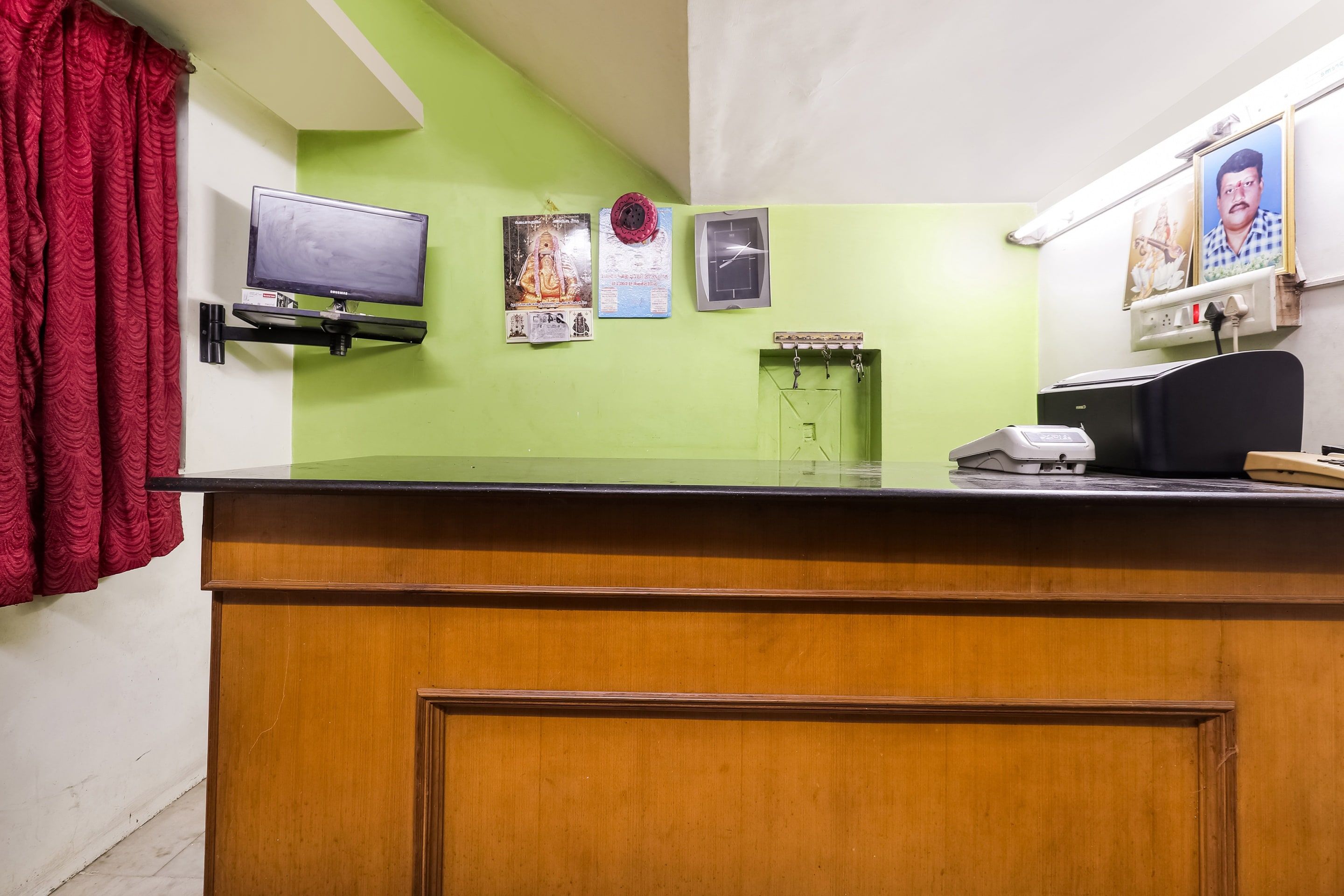 A reception desk with a flat-screen TV, a clock, and a calendar on the wall.