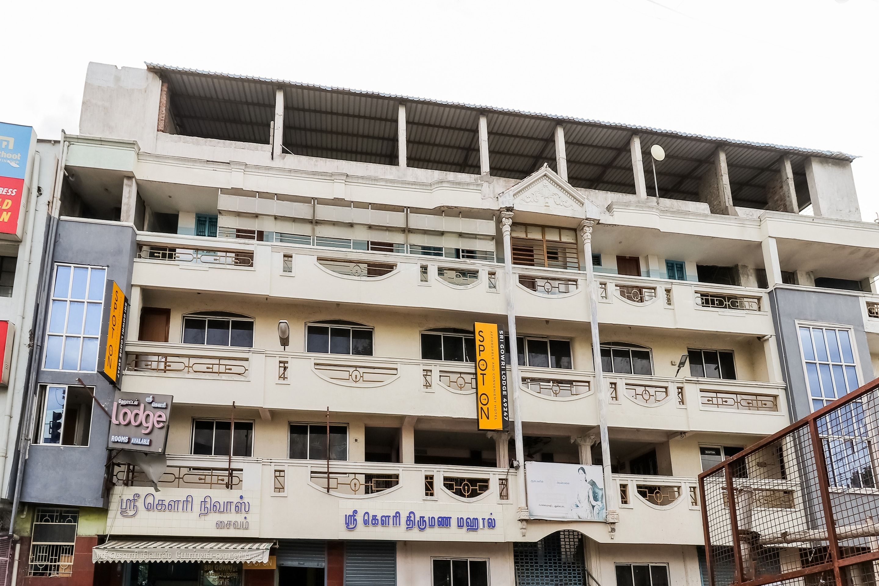 A multi-story building with balconies, signage for a hotel, and various storefronts.