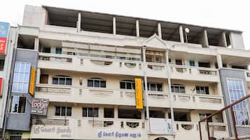 A multi-story building with balconies, signage for a hotel, and various storefronts.