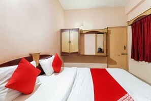 Una habitación de hotel con cama, armario, espejo y cortina roja.