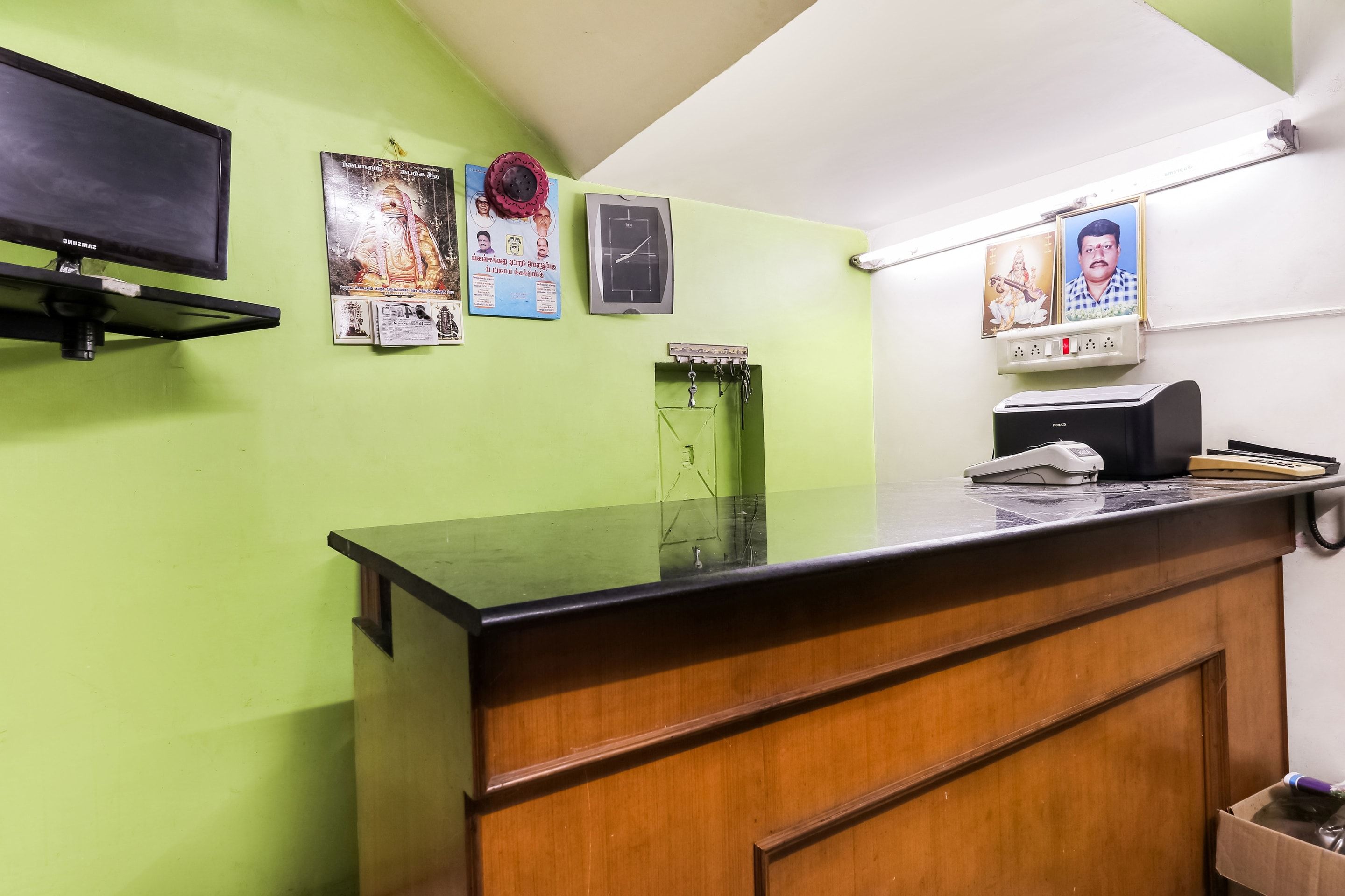 A reception area with a green wall, a black reception desk, and a wooden cabinet.