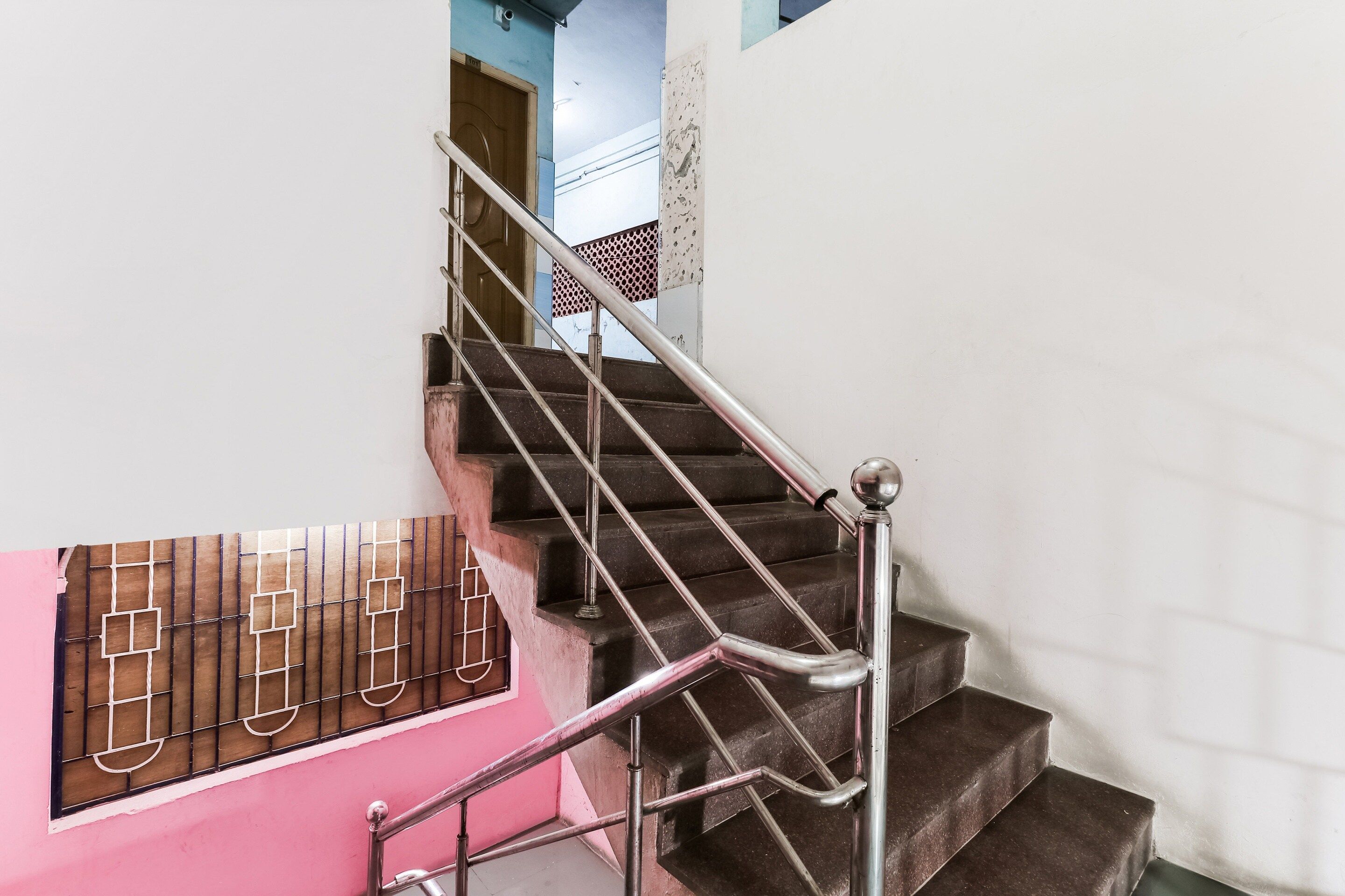 A staircase with metal railings and a pink wall.