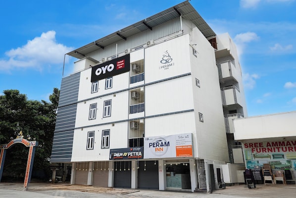 Un hotel de varios pisos con señalización que indica 'OYO Hotel Peram Inn' y 'PERAM INN'.