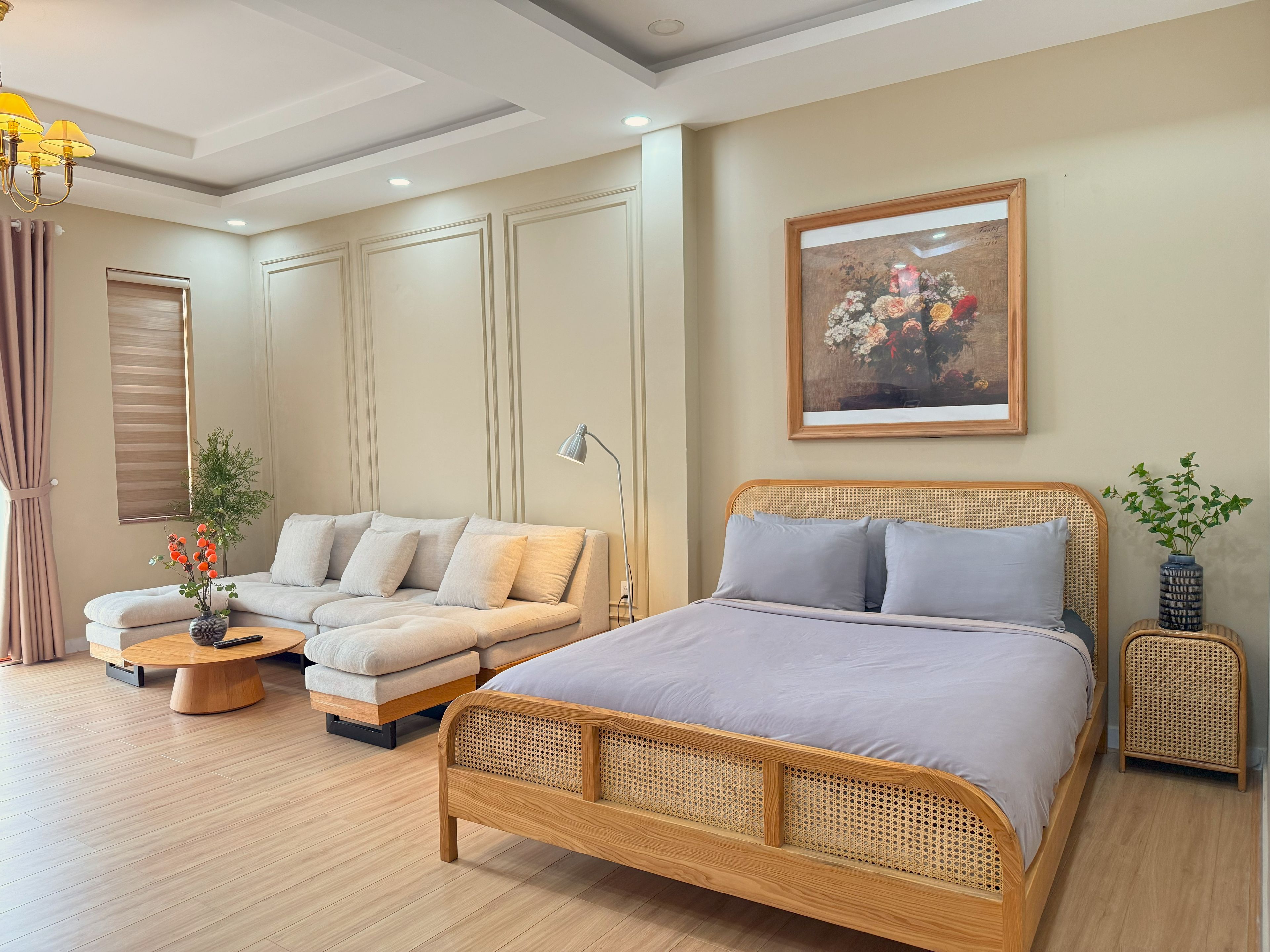 A modern bedroom with a wooden bed, a sofa, a small table, and a wall-mounted painting.