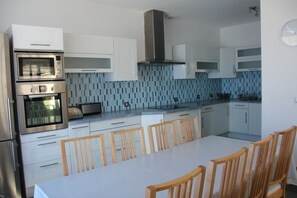 Een moderne keuken met witte kastjes, een roestvrijstalen oven en een betegelde spatwand.