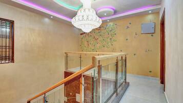 A modern interior with a glass railing staircase, a decorative wall mural, and a chandelier.
