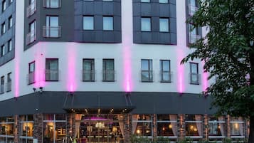 A multi-story hotel with a modern facade, large windows, and a ground-level restaurant.