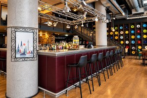 Eine Bar mit einer langen Theke, mehreren Hockstühlen und einem Stadtbild an der Wand.