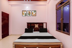 Quarto com cama de madeira, uma janela e três quadros na parede.