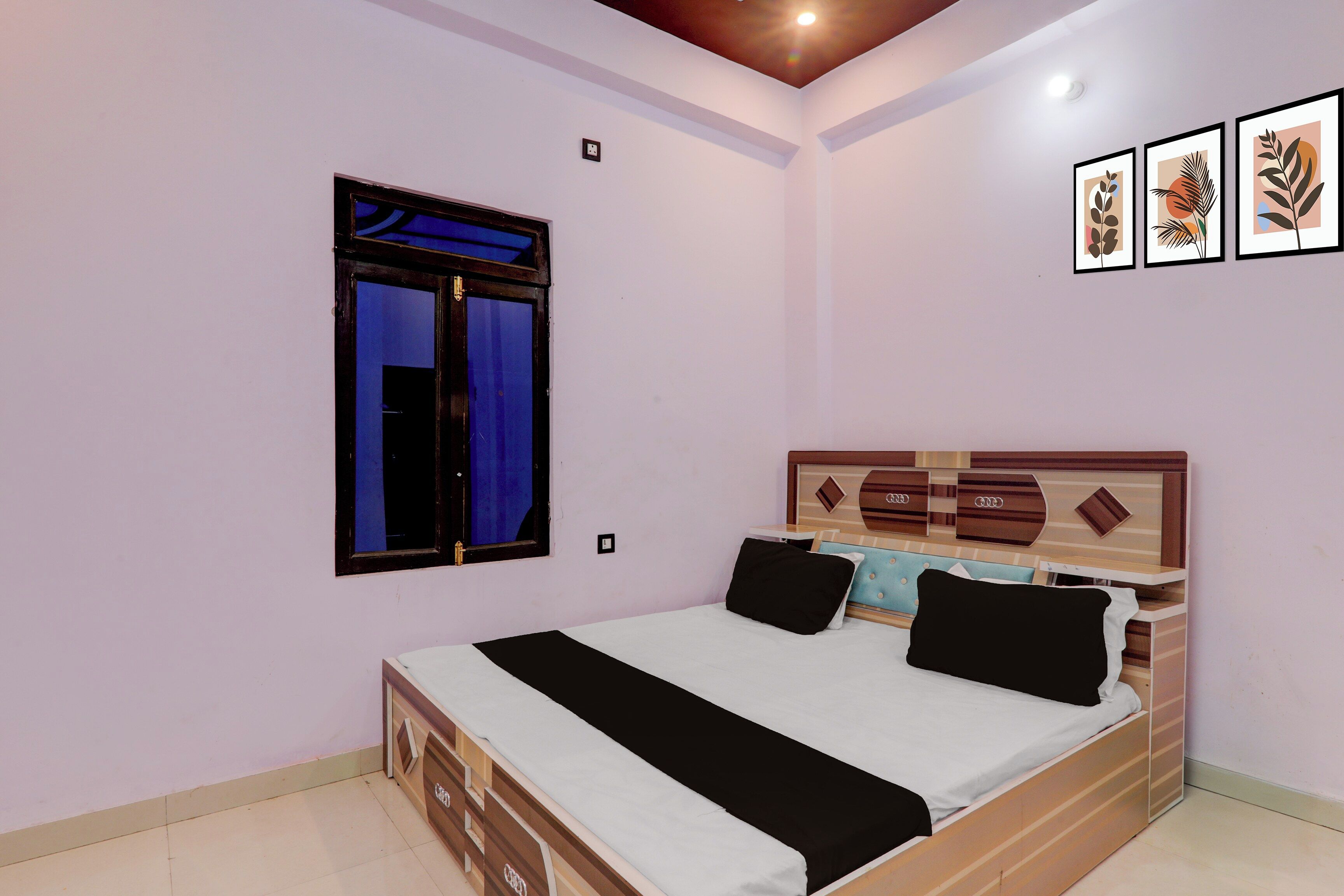 Quarto com cama, janela, tomada na parede e quadros decorativos.