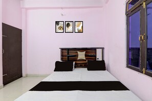 Quarto com cama, cabeceira de madeira, janela e três quadros na parede.
