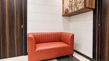 Una habitación con un sofá de cuero rojo, un armario de madera y una pared con azulejos que tiene una repisa arriba.