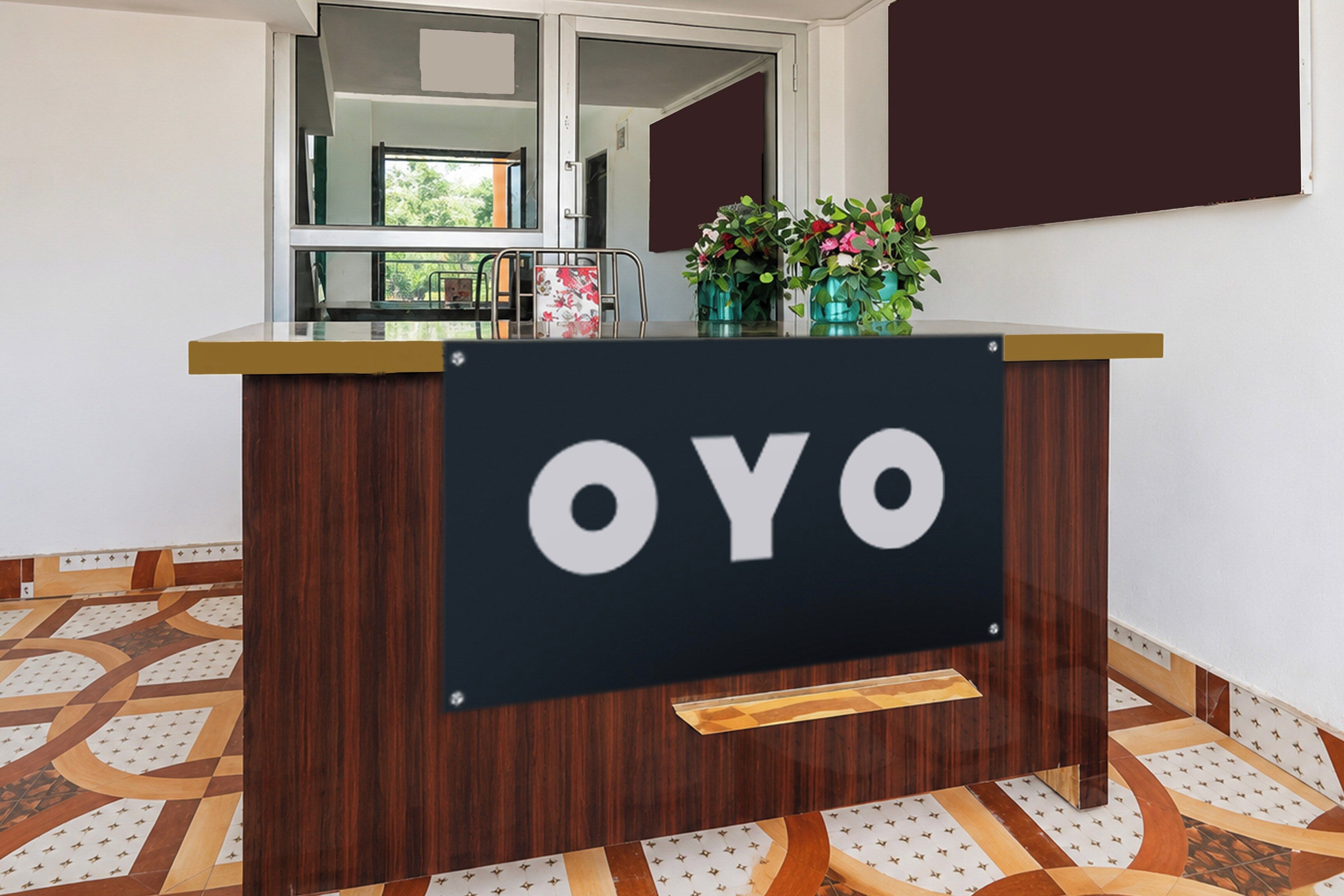 Un mostrador de recepción con un letrero que dice 'OYO' y vista al exterior a través de un ventanal.