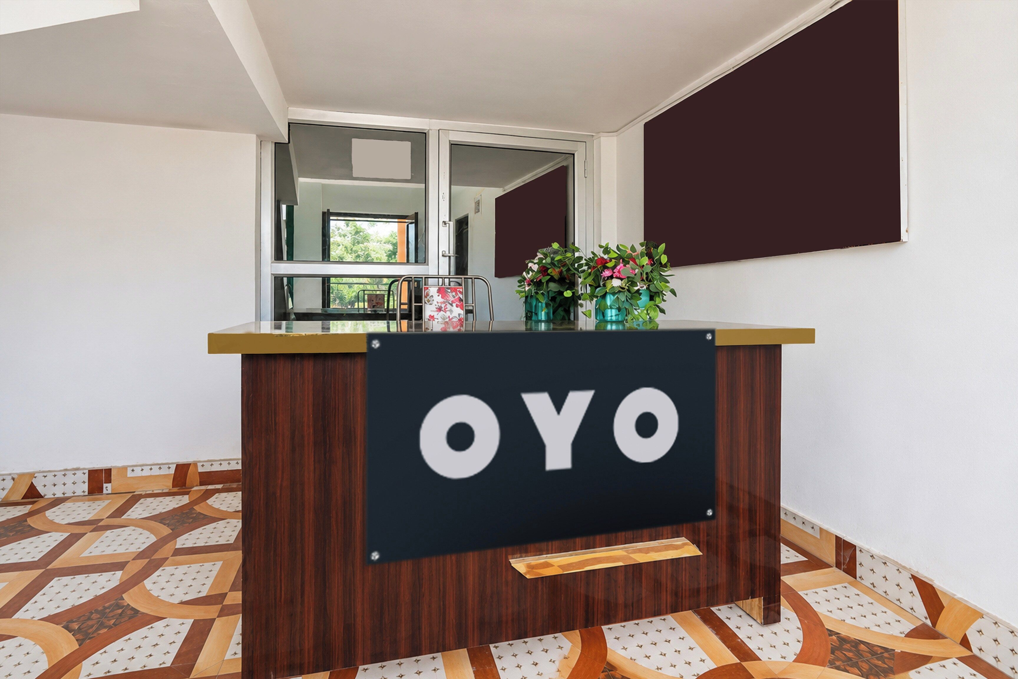 A reception desk with the word 'OYO' on it, a window with a view of greenery, and patterned flooring.