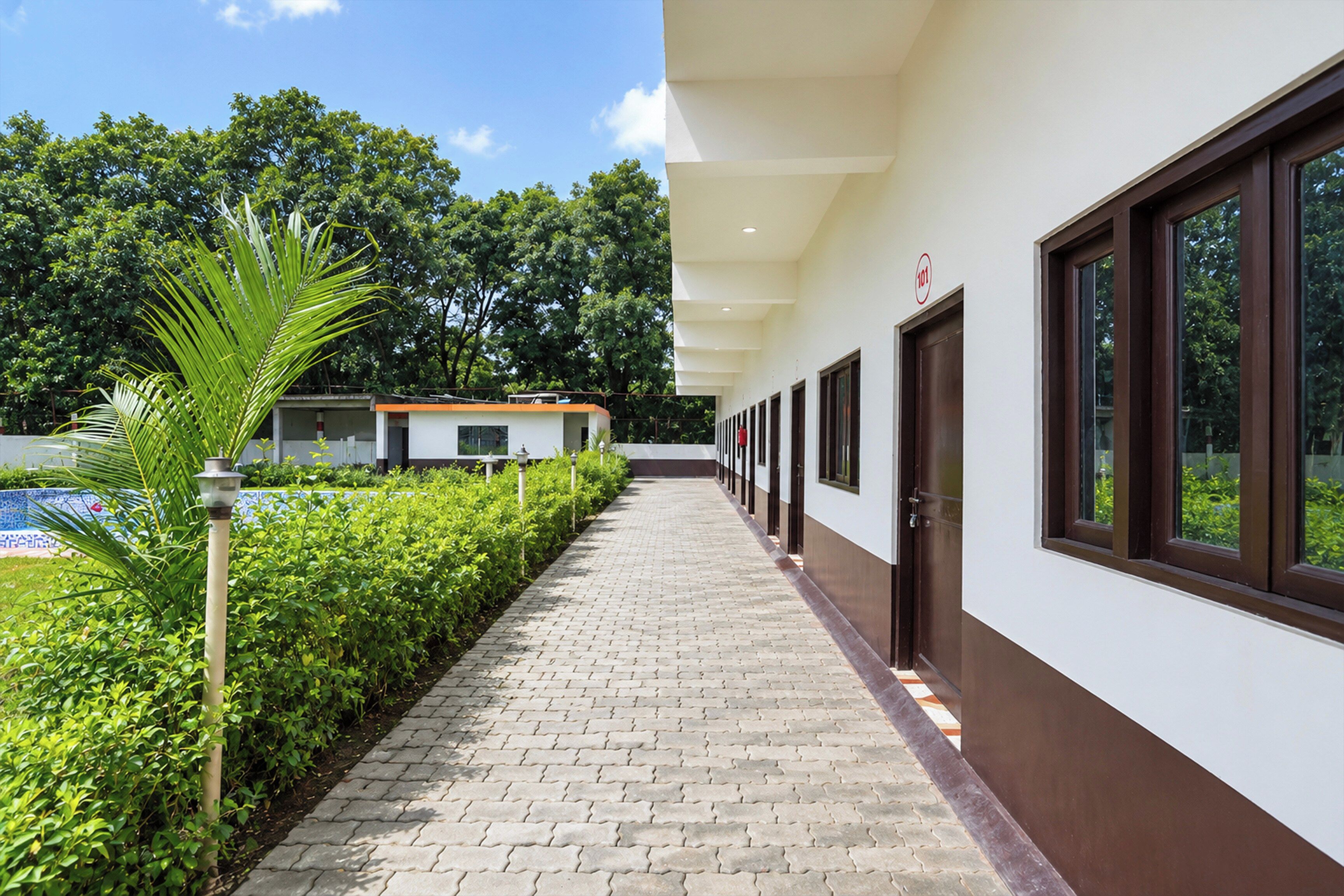 A corridor with a paved walkway, a row of doors, and a building with a sign indicating room number 101.