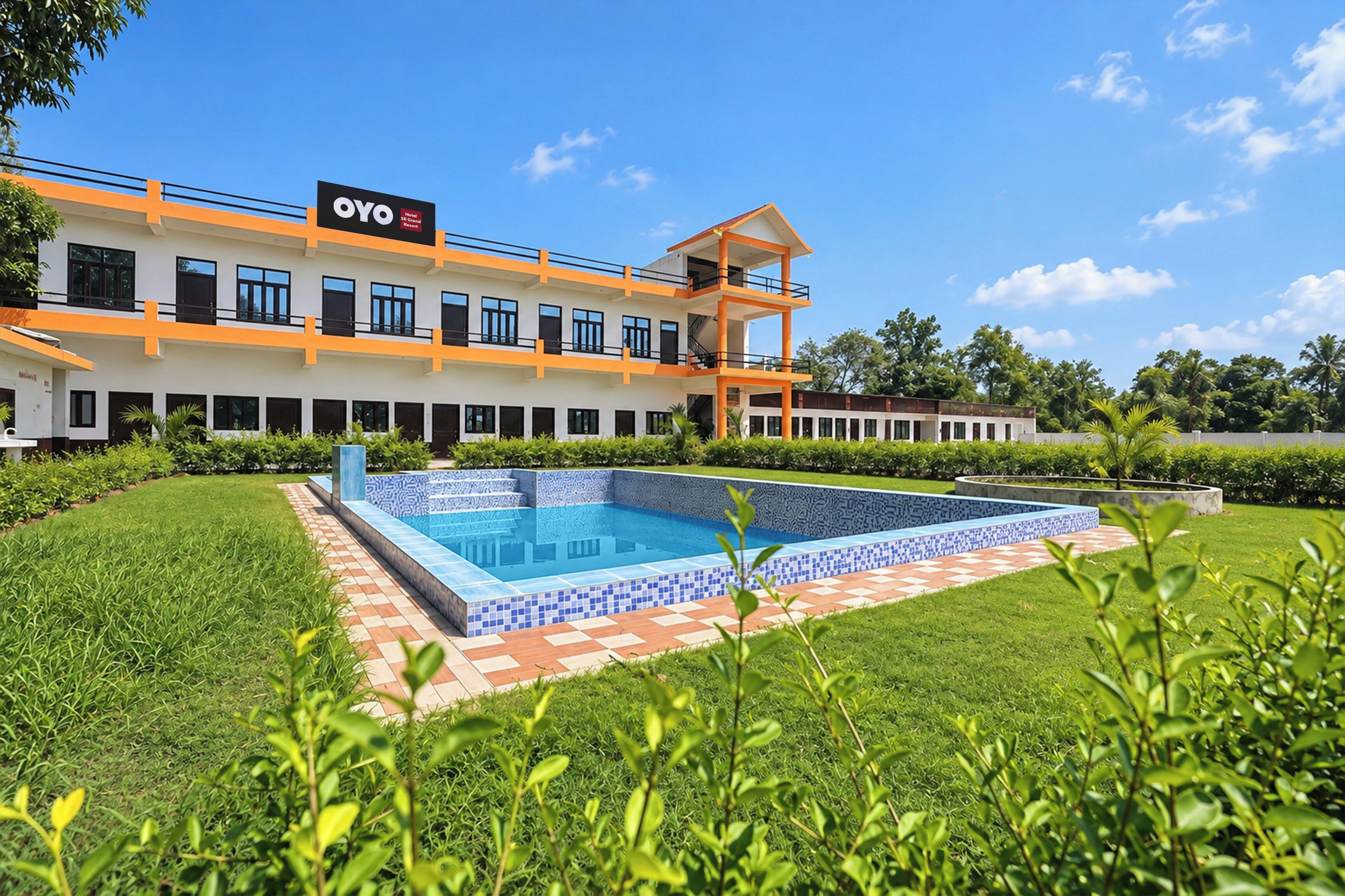 Un hotel con piscina, un edificio de dos pisos y un césped bien cuidado.