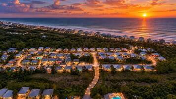 A coastal resort with multiple bungalow-style buildings, a winding road, and a visible swimming pool.