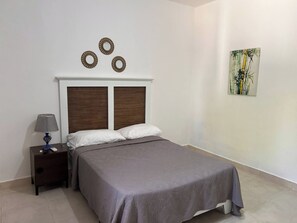 Ein Schlafzimmer mit Bett, Nachttisch, Lampe und Wandbild.