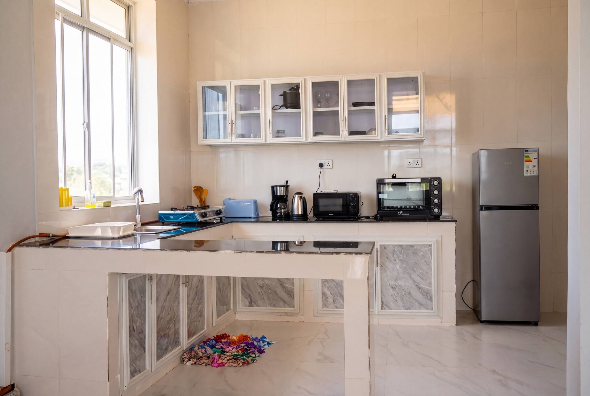 A modern kitchen with white cabinets, a built-in oven, a microwave, and a stainless steel refrigerator.