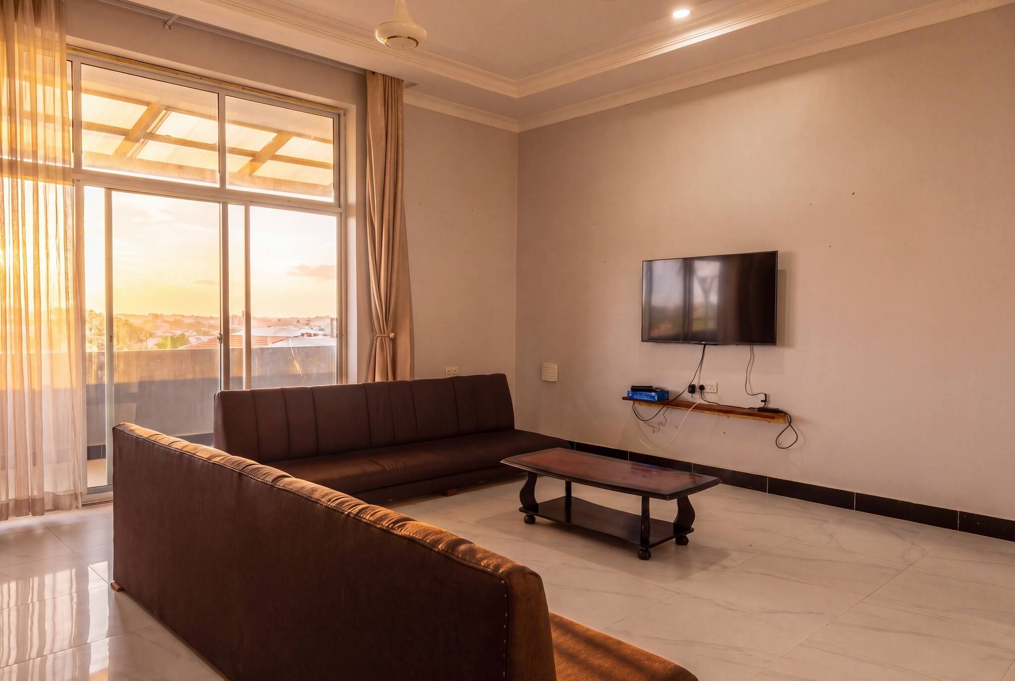 A modern living room with a sofa, a coffee table, and a flat-screen TV mounted on the wall.