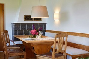 A dining area with a wooden table, chairs, a bench, a hanging lamp, and a wall-mounted light fixture. - Holiday home in Rimsting with swimming pool (Rimsting)