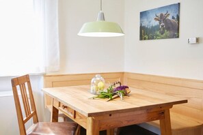 A wooden dining table with a bench, a pendant light, and a wall-mounted painting. - Holiday home in Rimsting with swimming pool (Rimsting)
