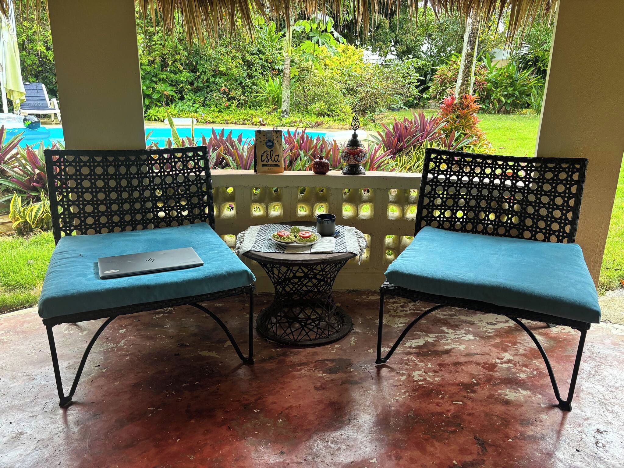 A patio with two chairs and a small table, surrounded by a railing with plants.