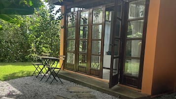 Un espace extérieur aménagé, abrité et doté d’une table et de chaises, entouré d’un chemin de gravier et de verdure.
