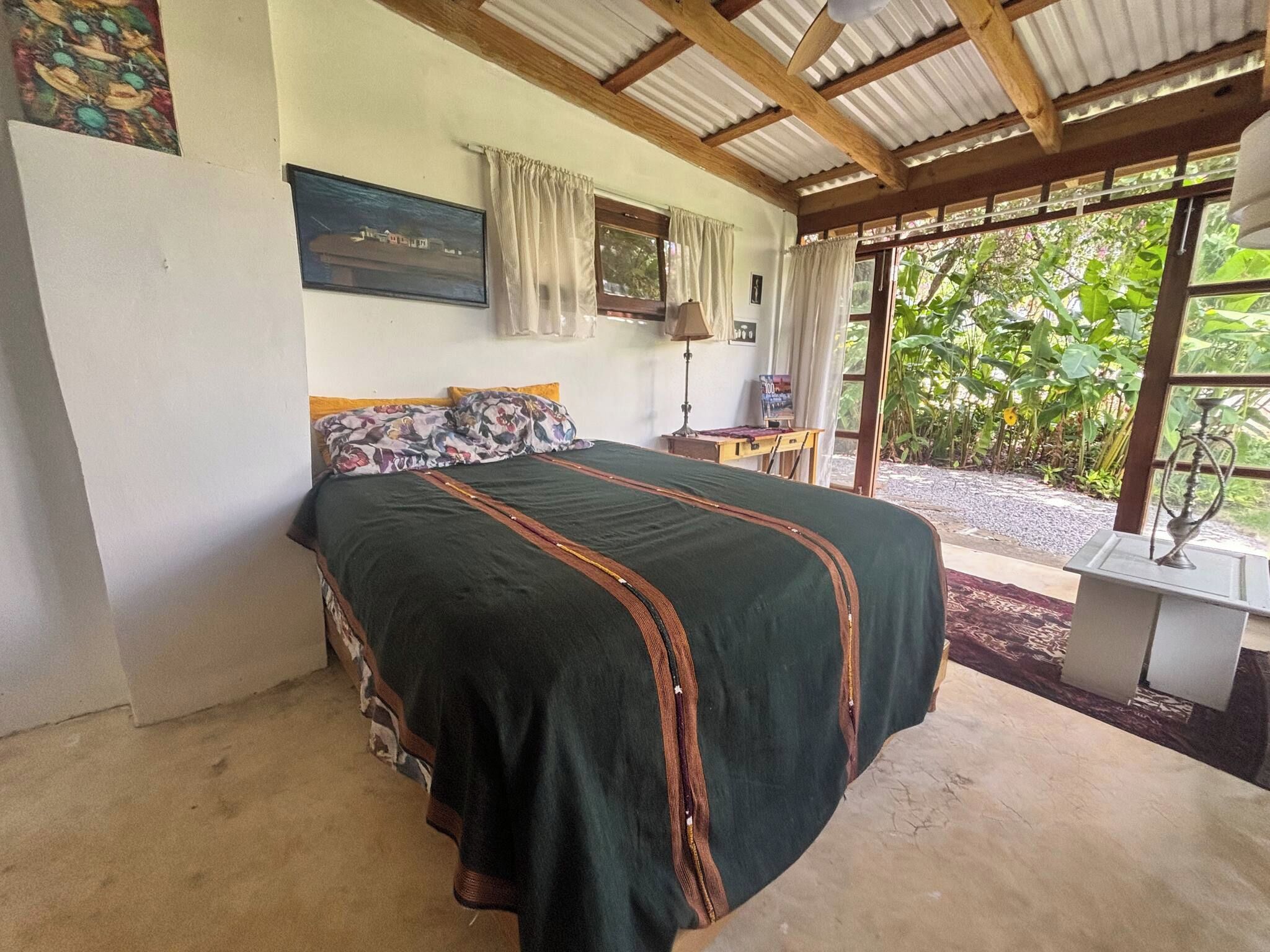 A bedroom with a bed, a nightstand, a lamp, and a window with curtains.