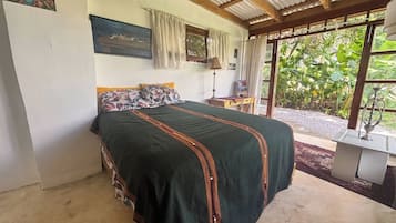 A bedroom with a bed, a nightstand, a lamp, and a window with curtains.